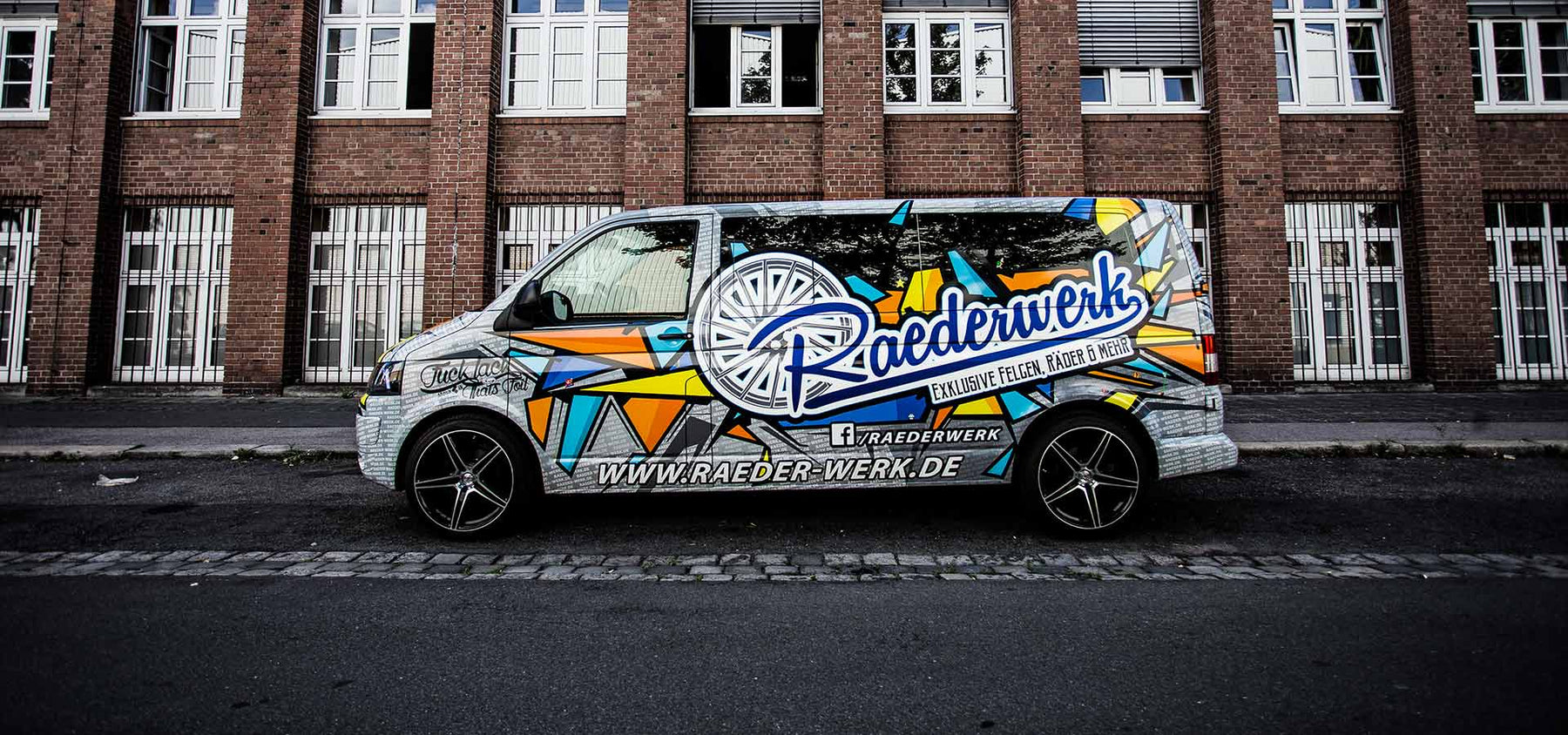 Folierter VW T5 von Räderwerk vor einer Backsteinfassade